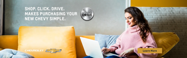 Woman sitting on yellow couch with laptop. Chevrolet Shop.Click.Drive. Makes purchasing your new Chevy Simple. 